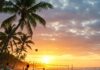10 Exciting Beach Activities to Add to Your Summer Bucket List Vibrant beach sunset with surfing, volleyball, and paddleboarding.